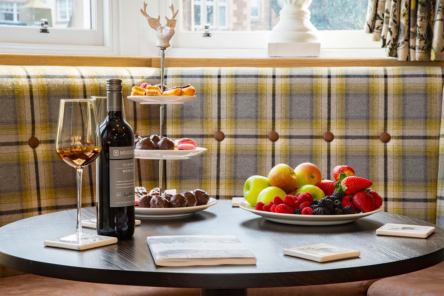 food and wine laid out on table next to a window