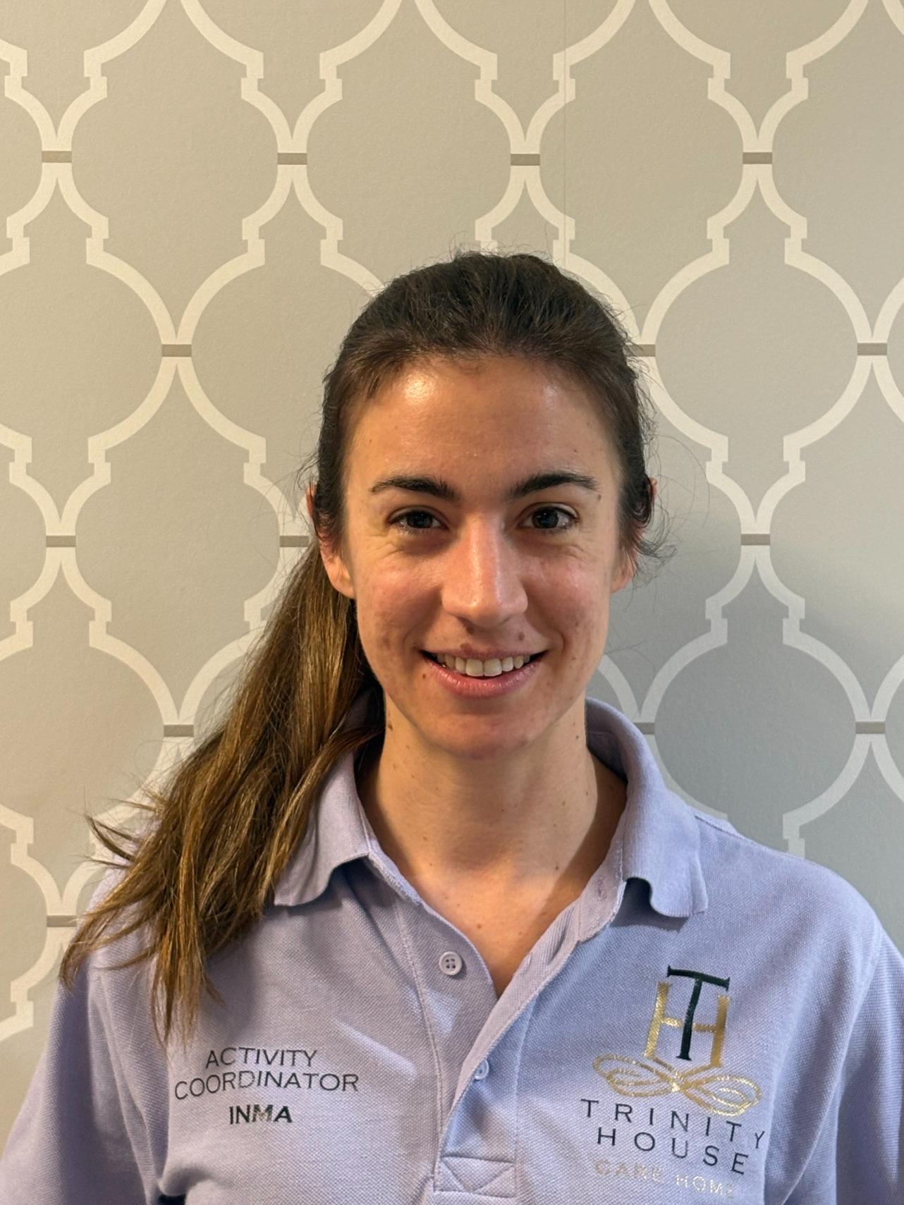 woman with brown ponytial in lilac polo shirt smiles for headshot