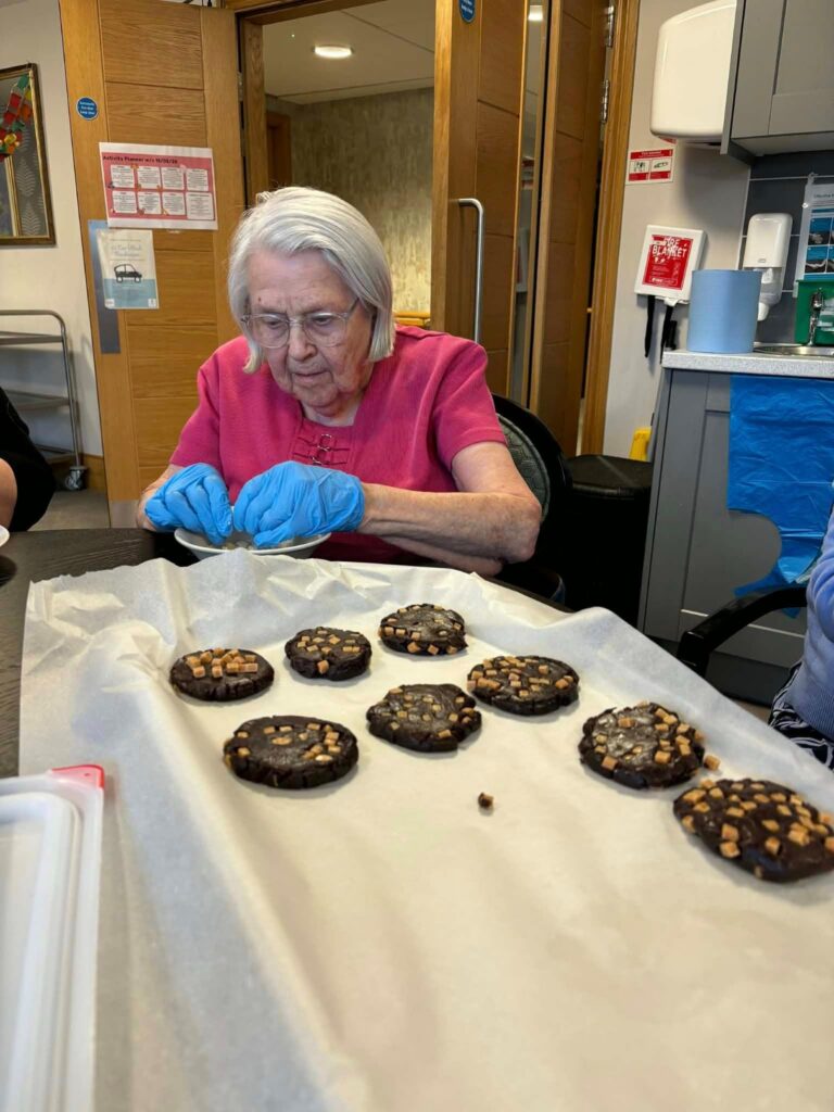 woman moulding cookies and placing them onto a baking tray