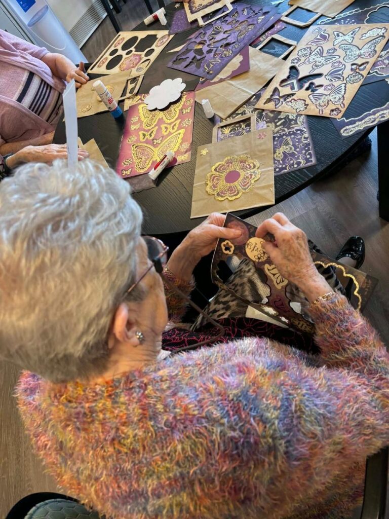care home resident decorating a gift bag with colourful stickers