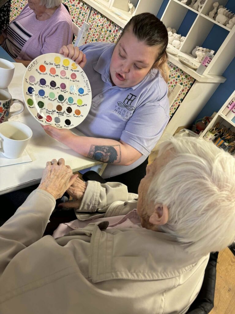 staff member showing a palette full of colours to a resident