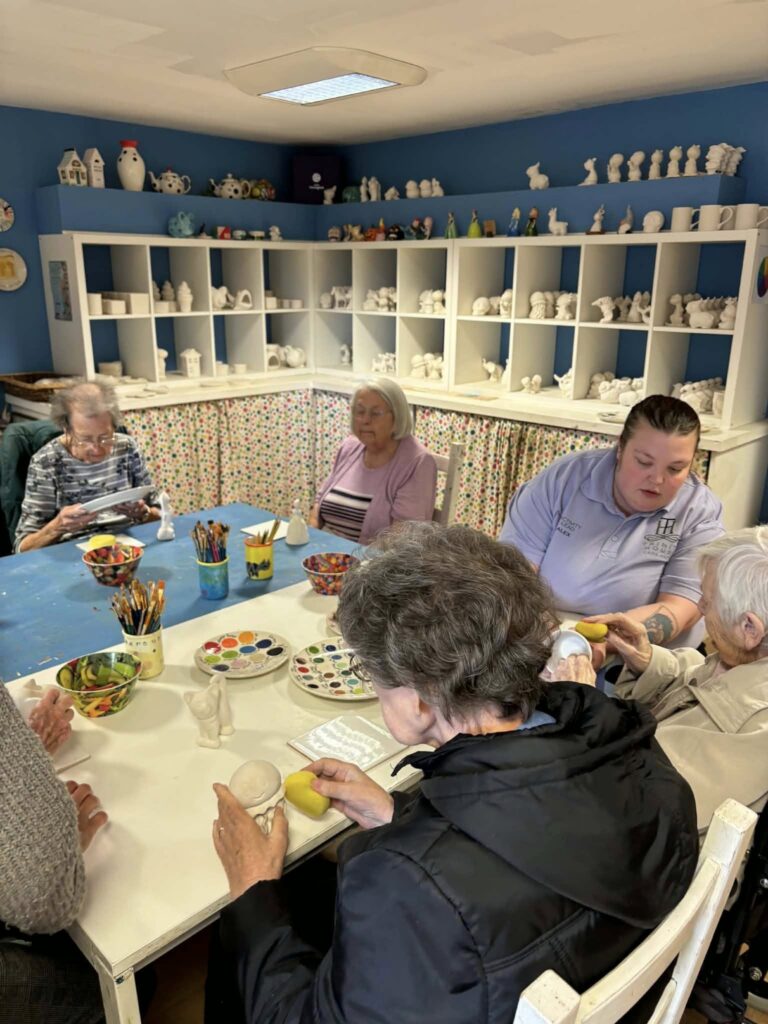 residents sat round a table at a pottery painting activity in edinburgh