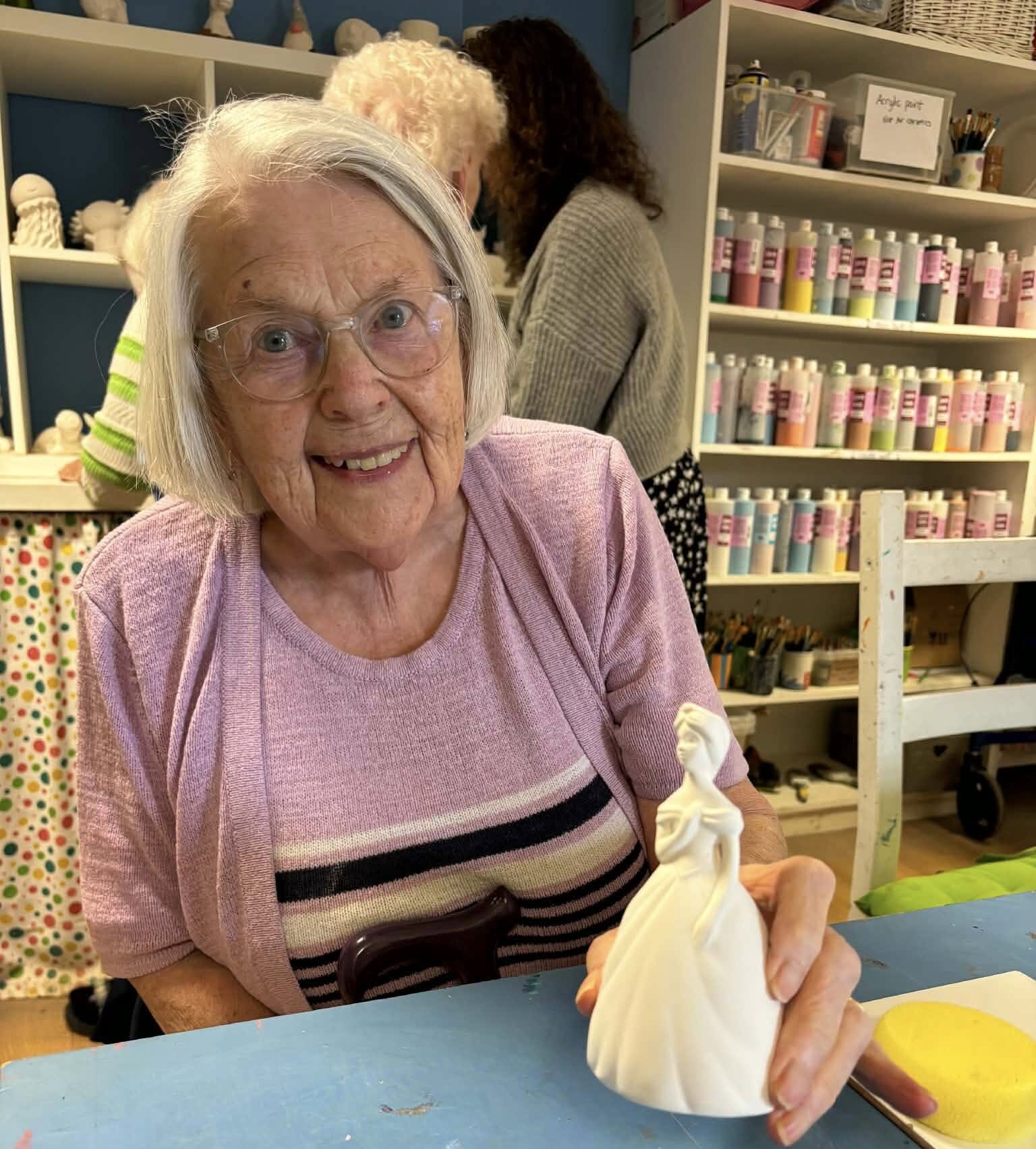 woman smiling and holding unpainted ceramic doll