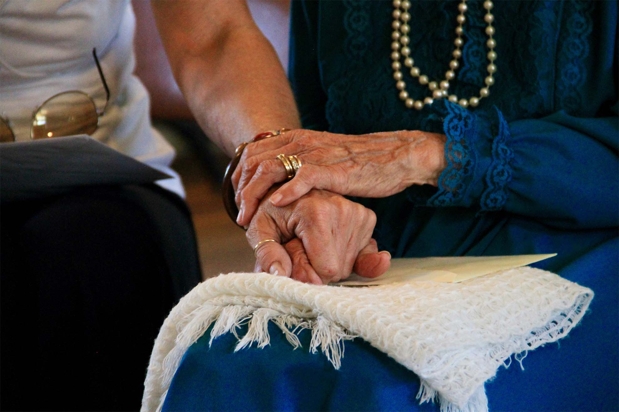 care home staff holding residents hands in comfort