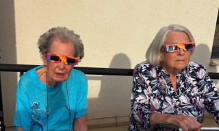 two residents watching the solar eclipse with glasses